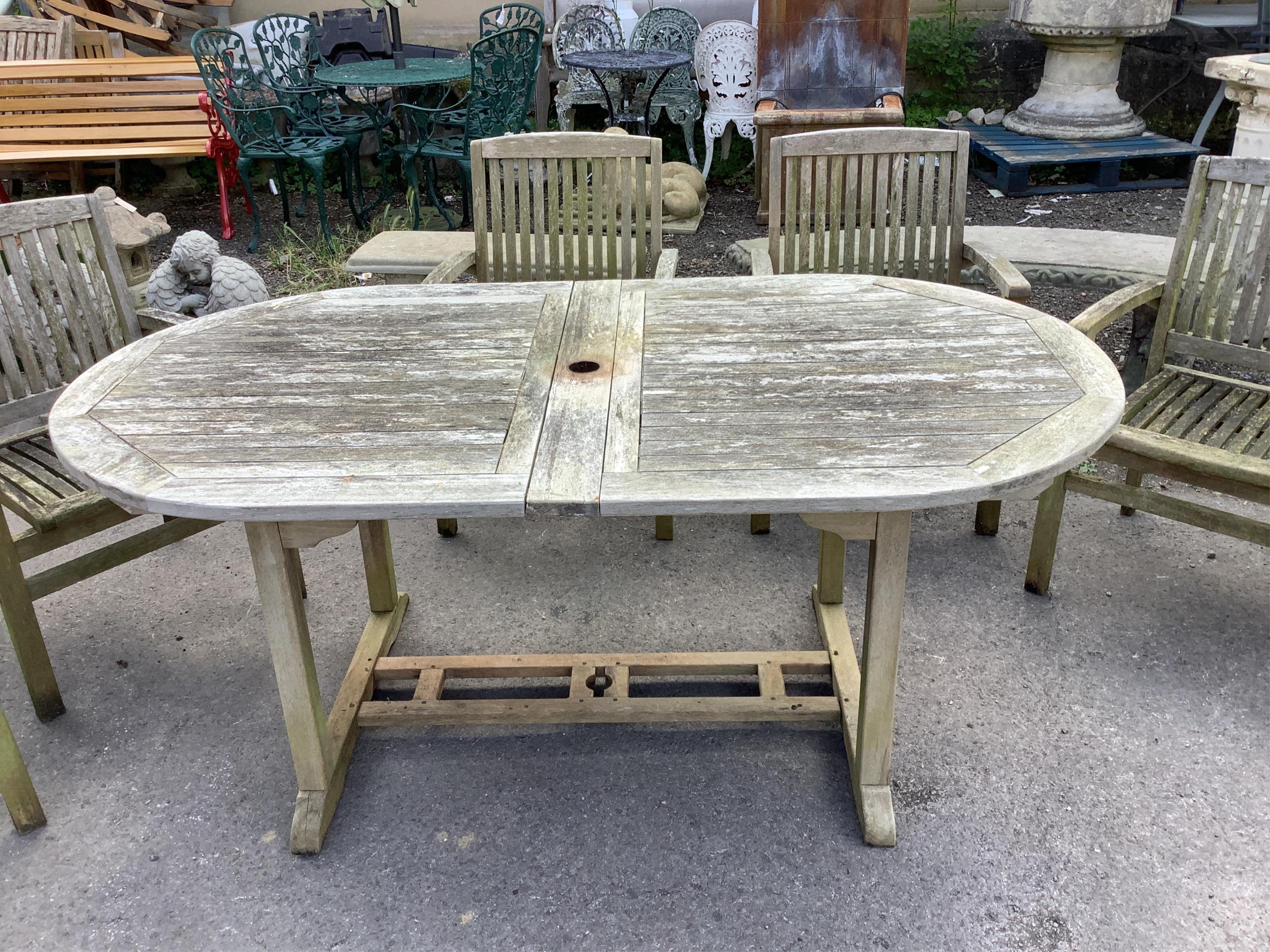 A “Kyoto” weathered teak extending garden table, width 240cm extended, depth 100cm, height 75cm, together with six stacking elbow chairs. Condition - fair